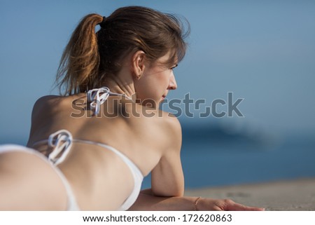 Girl at the sea. Slim girl lying down observing cruise liner