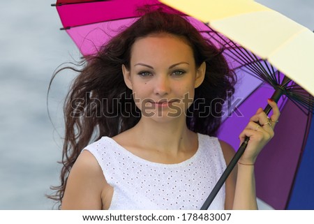 Portrait of brunette with umbrella. Young woman holds iridescent umbrella looking at camera