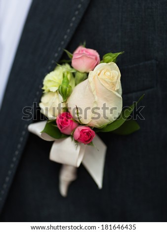 Boutonniere on groom's wedding jacket. White and pink rose wedding boutonniere on suit of groom