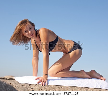 Attractive young woman in black swimsuit on all fours outdoors