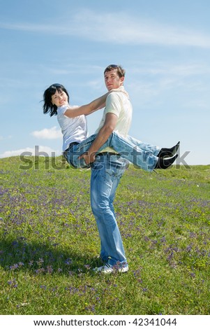 Attractive young man and woman are playing outdoors and are looking at camera