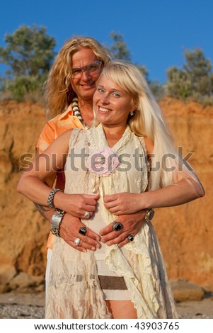 Young blond man and blond woman are posing and are looking at camera outdoors