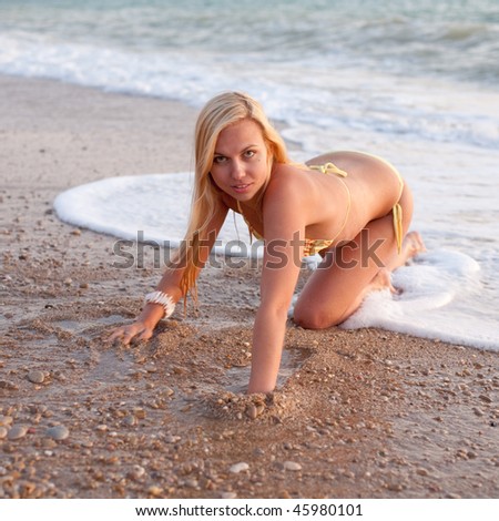 Attractive young long-haired blond woman in bikini at the sea