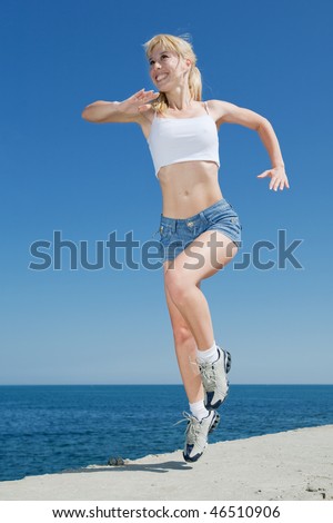 Vigorous blond woman in shorts and white shirt is running outdoors