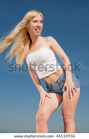 Long-haired blond woman in shorts and white shirt outdoors