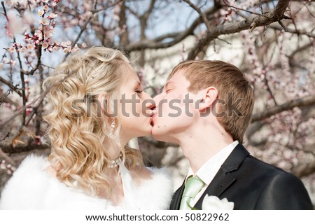 Just married among the flowers of blossoming apricot