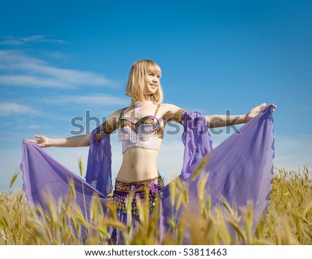 Slim girl in costume for oriental dance on field