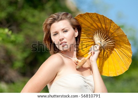 Young woman carrying yellow Chinese parasol outdoors