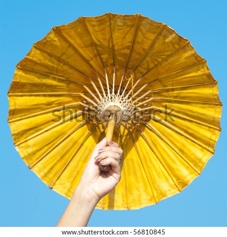 Hand carrying yellow Chinese parasol on background of the sky