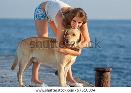 Young woman with Labrador male dog on the background of the sea. Girl embracing her dog