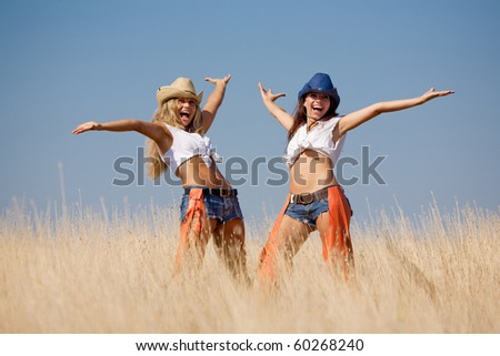 Two girls at the field. Young women in costumes of cowboys outdoors