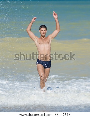 Attractive young man at the sea. Young man playing on the beach