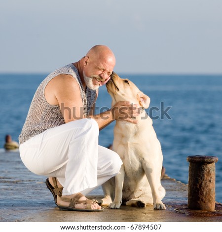Middle-aged man with Labrador female dog on the coast of the sea