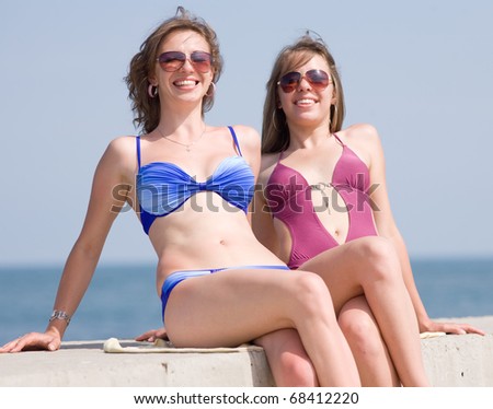 Girls in bikini at the sea. Two attractive girls in bikini looking through sunglasses in camera