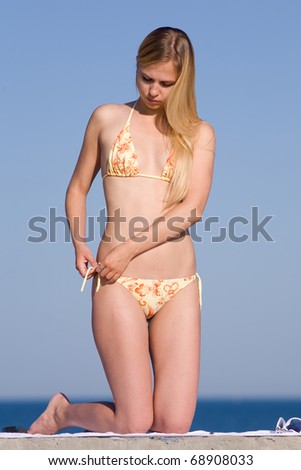 Girl at the sea. Attractive young woman in bikini on background of clear sky