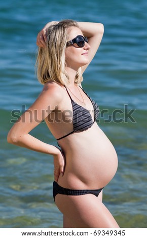 Pregnant woman in swimwear at the sea. Attractive expectant mother in bikini