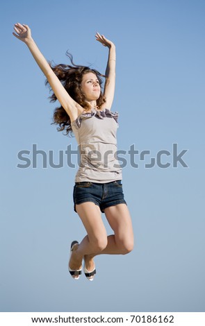 Girl jumping. Young brunette jumping on background of sky