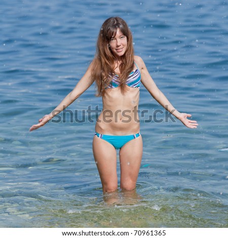 Attractive girl in bikini at the sea. Slim girl in bikini is splashing at the sea