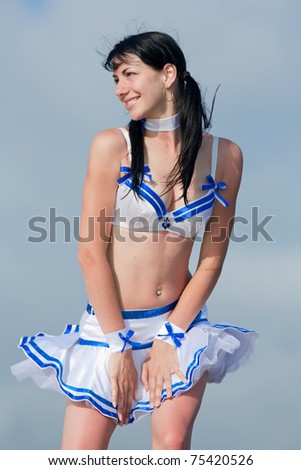 Brunette in costume for a dance outdoors. Young woman holds her skirt blown by wind