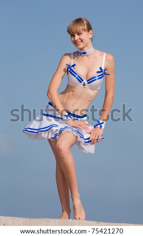 Blonde in dancing suit outdoors. Young woman holds her skirt blown by wind