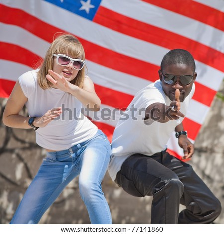 White girl and black guy dancing outdoors. White girl and black guy on background of American flag