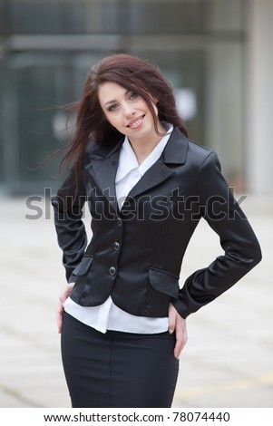 Portrait of attractive business woman on background of building. Cute business woman outside on a grey day