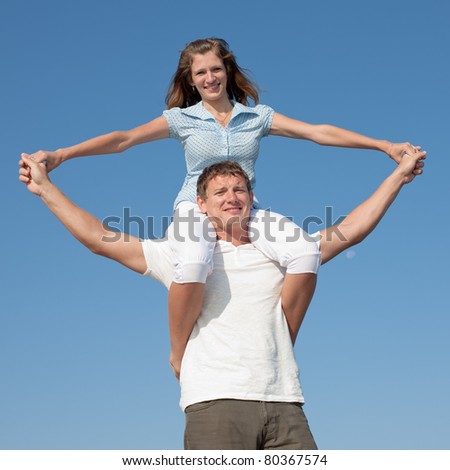 Piggyback. Attractive couple playing outdoors. Young man carrying girl on his back