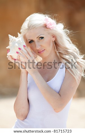 Attractive blonde with shell on the beach. Portrait of blonde on open air