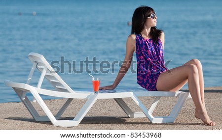 Attractive brunette on the beach. Young woman in purple dress posing on open air.
