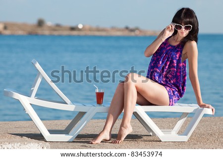 Attractive brunette on the beach. Young woman in purple dress posing on open air.