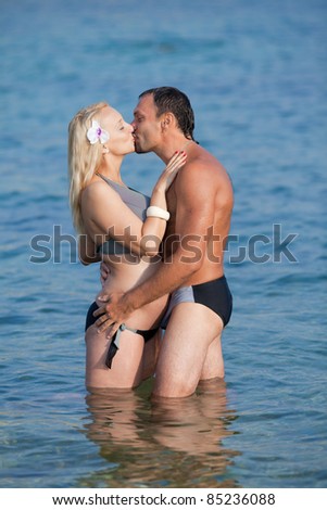 Attractive couple at the sea. Middle aged man and young pregnant woman in sea