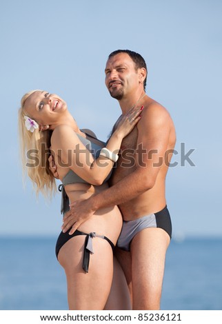Attractive couple at the sea. Middle aged man and young pregnant woman on the beach