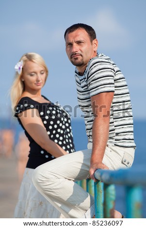 Attractive couple at the sea. Middle aged man and young pregnant woman on the beach
