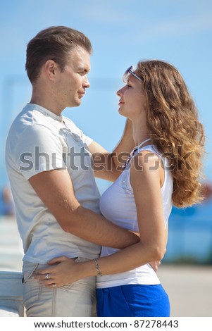 Attractive couple on pier. Young man embracing his wife smiling