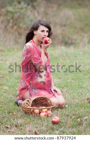 Pregnant woman in the autumn park. Expectant mother eats apples on open air