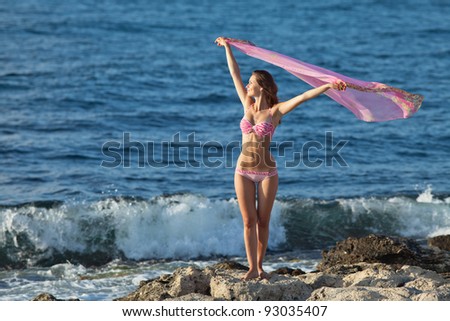 Girl at the sea. Attractive young woman on background of sea. Lady in pink swimwear on the beach