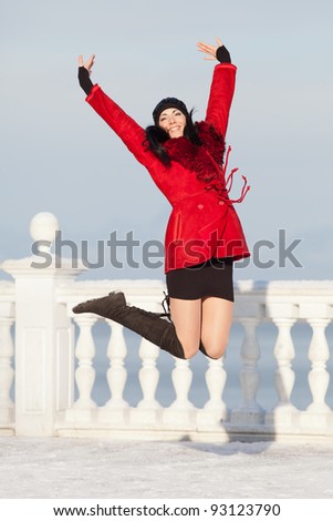 Beautiful young woman at winter. Attractive brunette in red jumping in the winter park