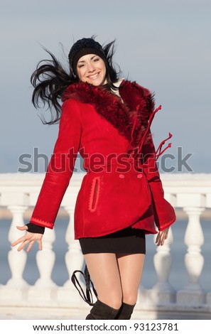 Beautiful young woman at winter. Attractive brunette in red jumping in the winter park