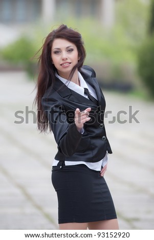 Attractive business woman on background of building. Cute business woman showing pointing fingers looking at camera