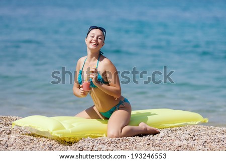 Girl at the sea. Attractive young woman sitting on swimming mattress looking at camera smiling