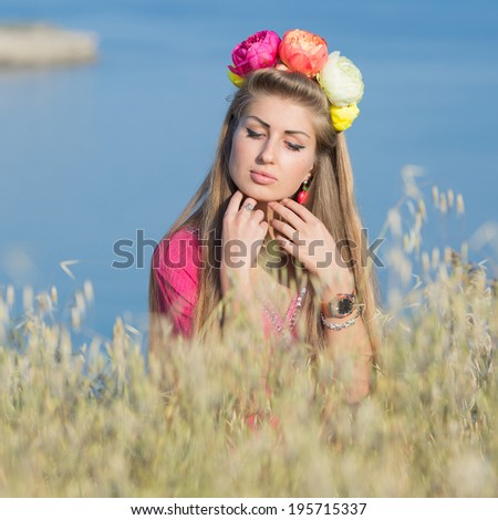 Portrait of long-haired girl outdoors. Young woman in flower wreath posing on background of sea
