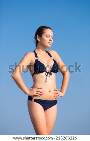 Girl in bikini outdoors. Young woman in dark bikini posing hands on your hips