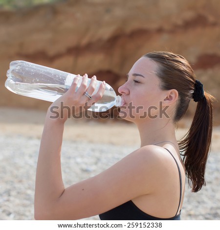 Girl drinks. Young woman with ponytail drinks water from a plastic bottle of 1.5 liters