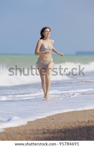 Girl runs with along the beach. Attractive young woman runs along the beach