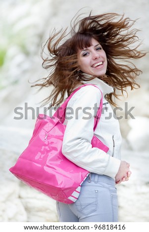 Attractive girl with pink bag on open air. Attractive brunette with pink bag looking at camera smiling outdoors