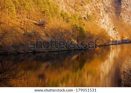 Small cottage in mountain forests with reflections in water.