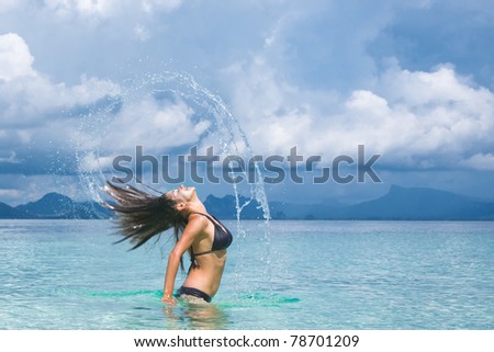 Splash of water made by hair of young woman swimming in the sea