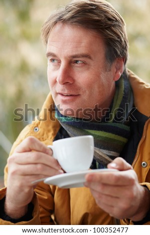 Man In Outdoor CafÃ?Â?Ã?Â½ With Hot Drink  Wearing Winter Clothes