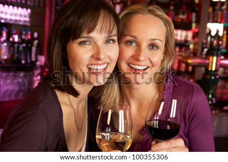 Two Women Enjoying Drink Together In Bar