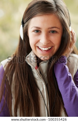 Teenage Girl Wearing Headphones And Listening To Music Wearing Winter Clothes